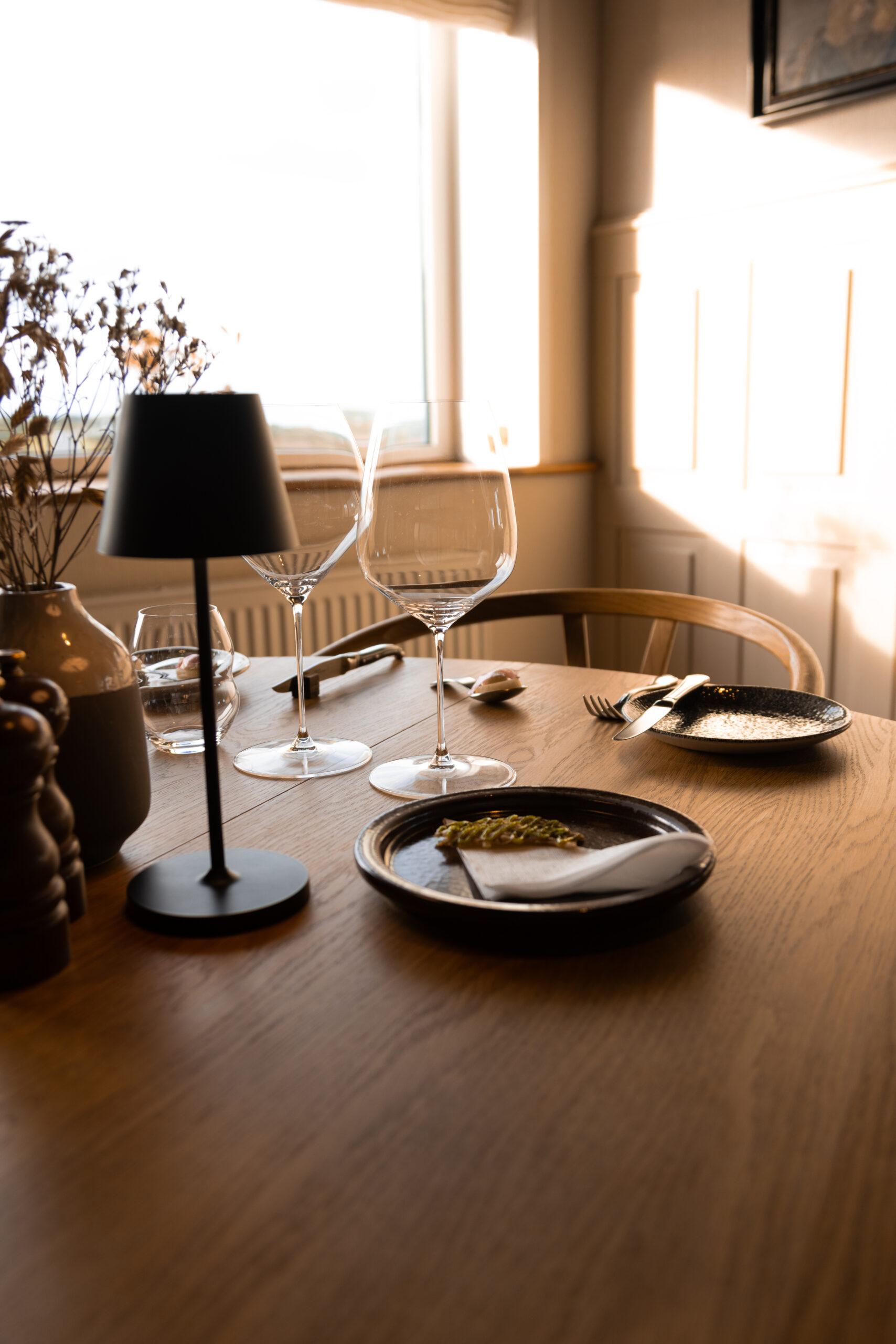 Gæster nyder en aften i stearinlysets skær på Nymindegab Kro med gastronomi og fjordudsigt.